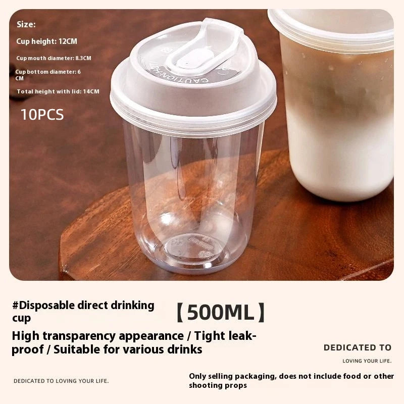 A clear disposable coffee cup with a lid is shown on a wooden surface, next to a larger white cup.