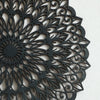 Decoración de pared de mandala de madera gris oscuro con intrincados patrones recortados.