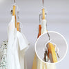 A set of space-saving hanger connector hooks used to hang white clothing on wooden hangers.