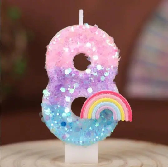 A large number eight candle decorated with iridescent glitter and a rainbow design.