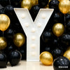 A large white marquee letter Y made of balloons in gold and black for party decor
