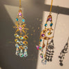 A delicate gold crystal suncatcher wind chime ornament featuring purple and blue gemstones.