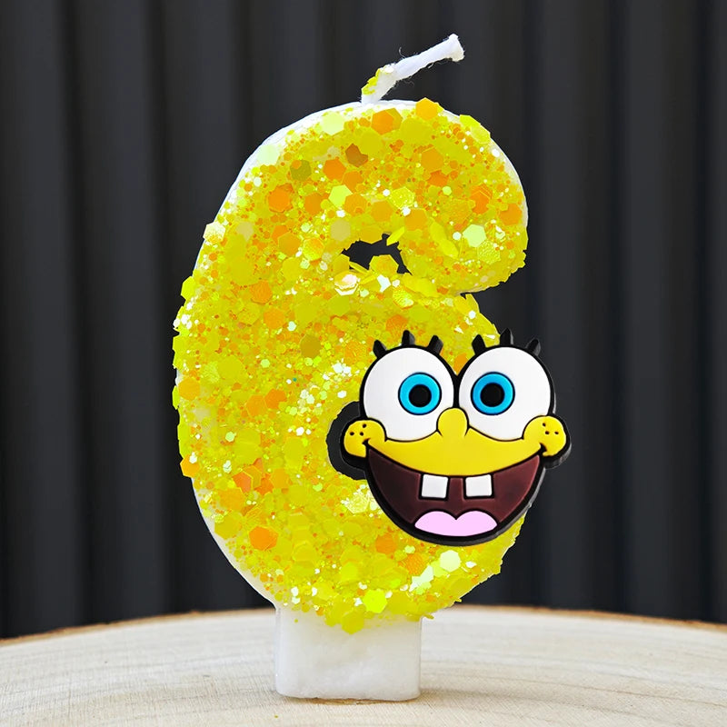 A yellow sponge cake candle shaped like the number 6, featuring a cartoon face design.