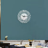 A white acrylic wall clock with intricate Arabic calligraphy design mounted on a teal wall.