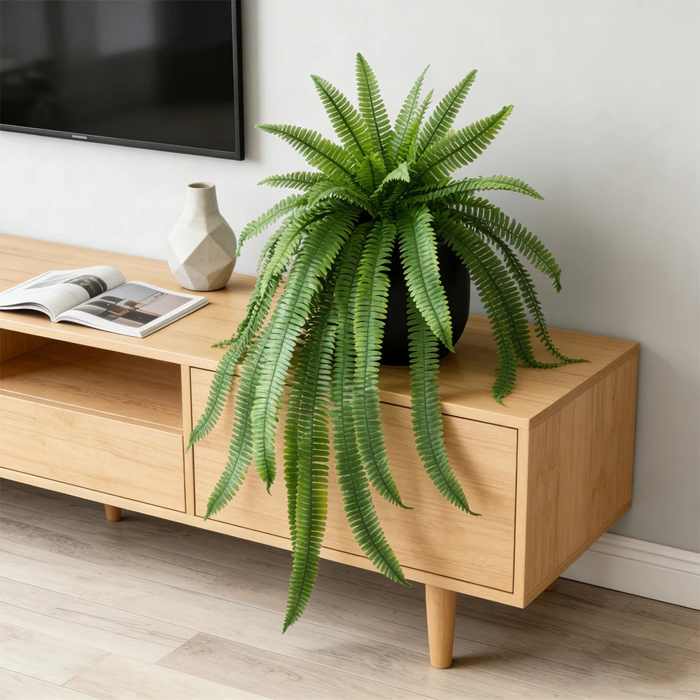 A potted artificial Persian fern hanging vine with long green fronds on a wooden shelf.