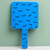 A bright blue handheld vanity mirror with an ergonomic handle featuring a pattern of black eyelashes.