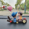 A set of cute couple balloon car ornaments featuring a girl and a boy figure on a wooden log.