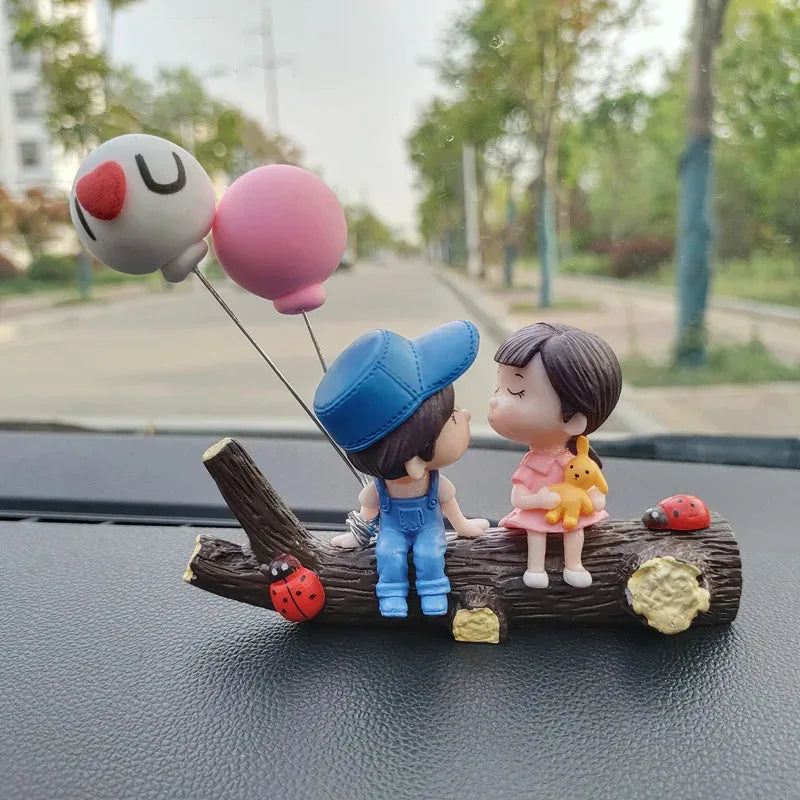 A set of cute couple balloon car ornaments featuring a girl and a boy figure on a wooden log.