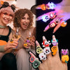 A hand displays a set of glowing Halloween rings on fingers, with a woman smiling in the background.