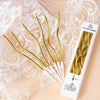 A set of gold curved decorative birthday candles displayed on sheer lace fabric.