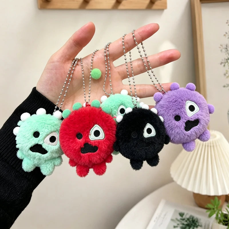 A hand holds several colorful plush keychains with clear photocard holders, featuring green, red, black, and purple designs.