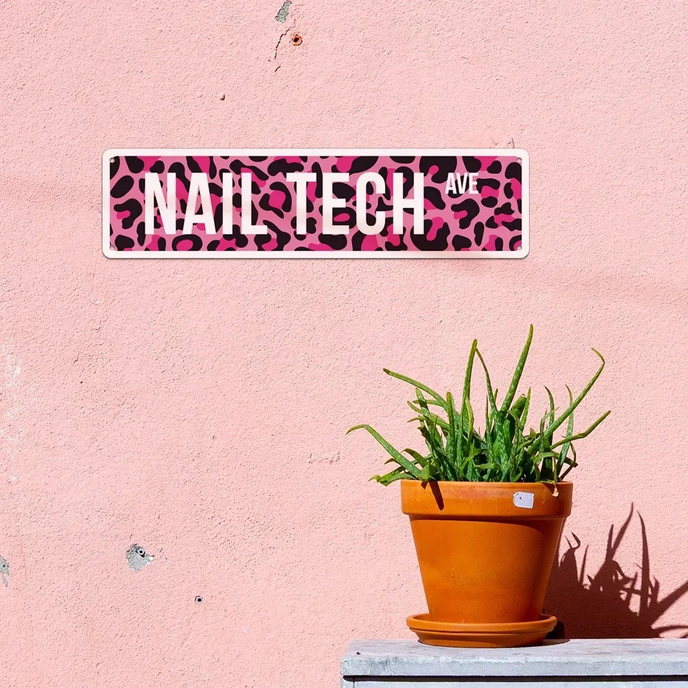 A pink wall sign with black leopard print featuring the text NAIL TECH AVE