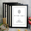A set of five black wooden photo frames with a minimalist design displayed against a gray concrete background.