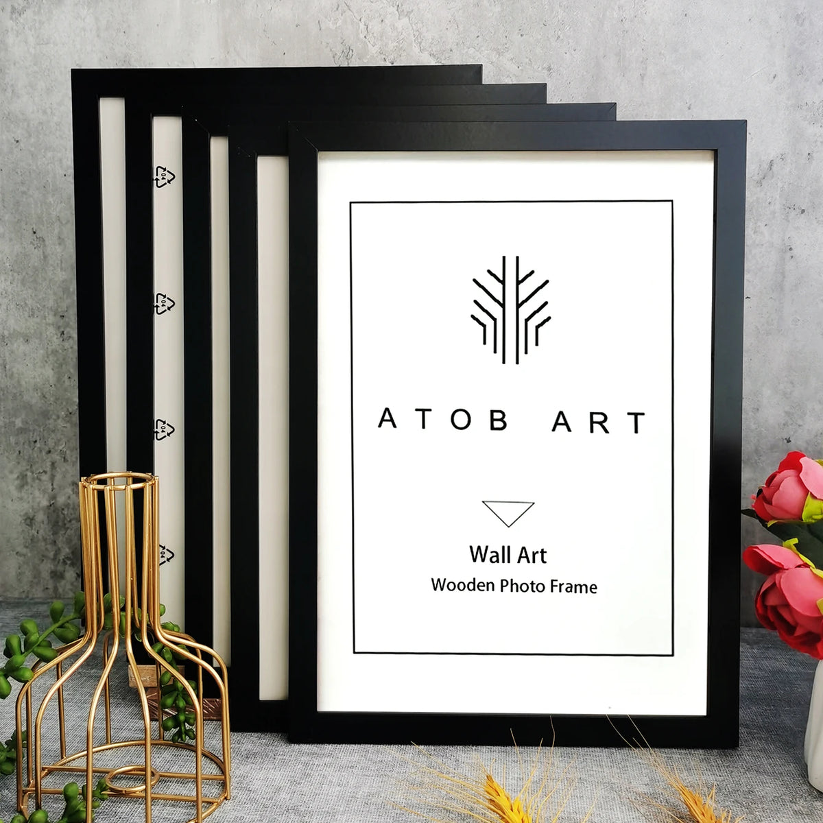 A set of five black wooden photo frames with a minimalist design displayed against a gray concrete background.