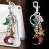 Silver moon and stars charm keychain attached to a white leather bag