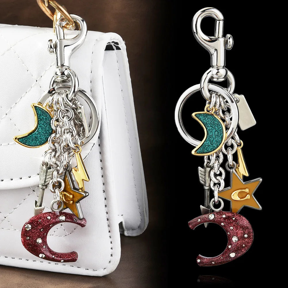 Silver moon and stars charm keychain attached to a white leather bag