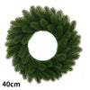 A green artificial Christmas wreath with red berries and a velvet bow.