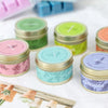A collection of natural soy wax travel candles in various colors including green, yellow, pink, and lavender.
