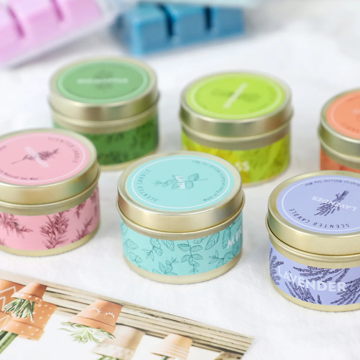 A collection of natural soy wax travel candles in various colors including green, yellow, pink, and lavender.