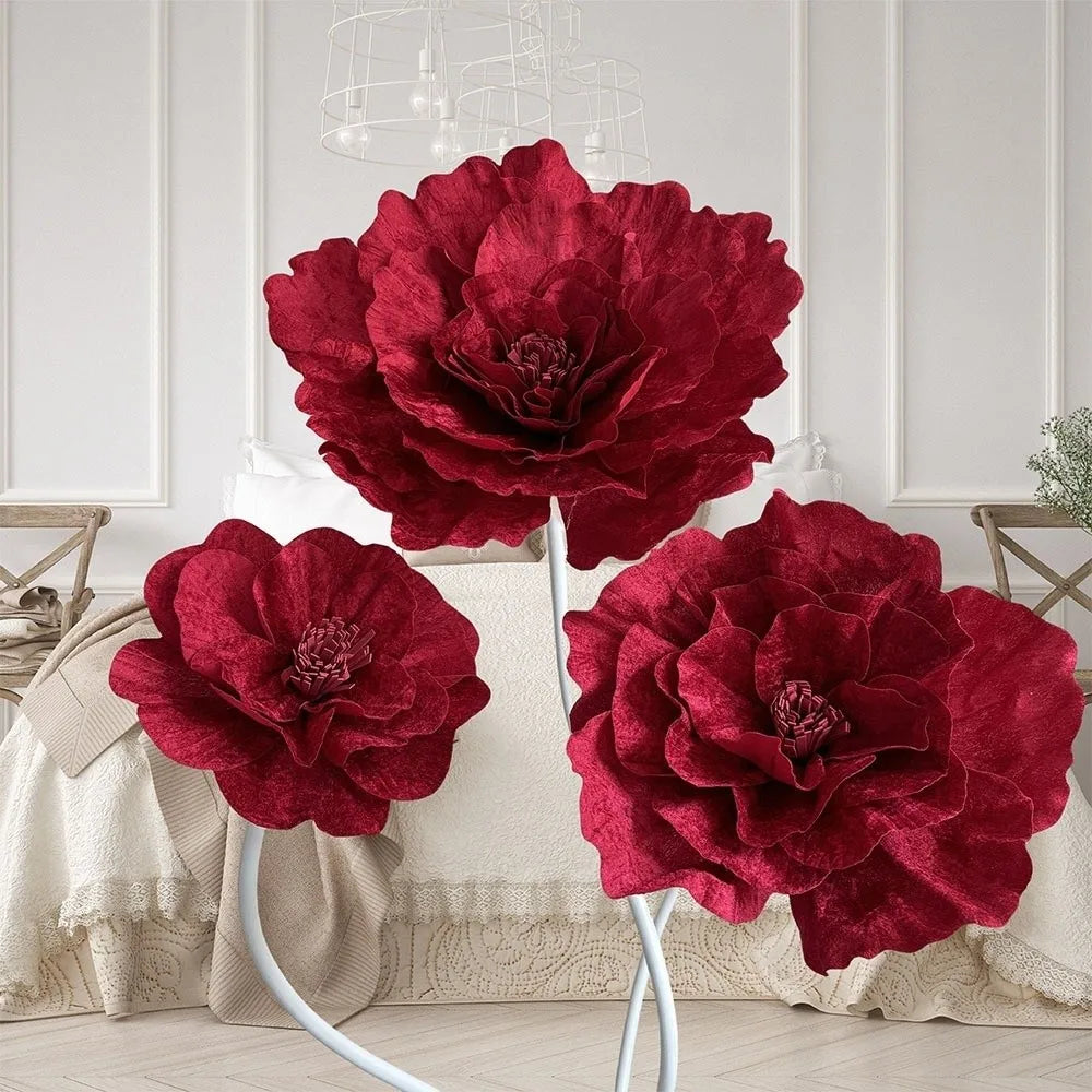 A bouquet of large, deep red velvet artificial peony flowers displayed on a white stand.
