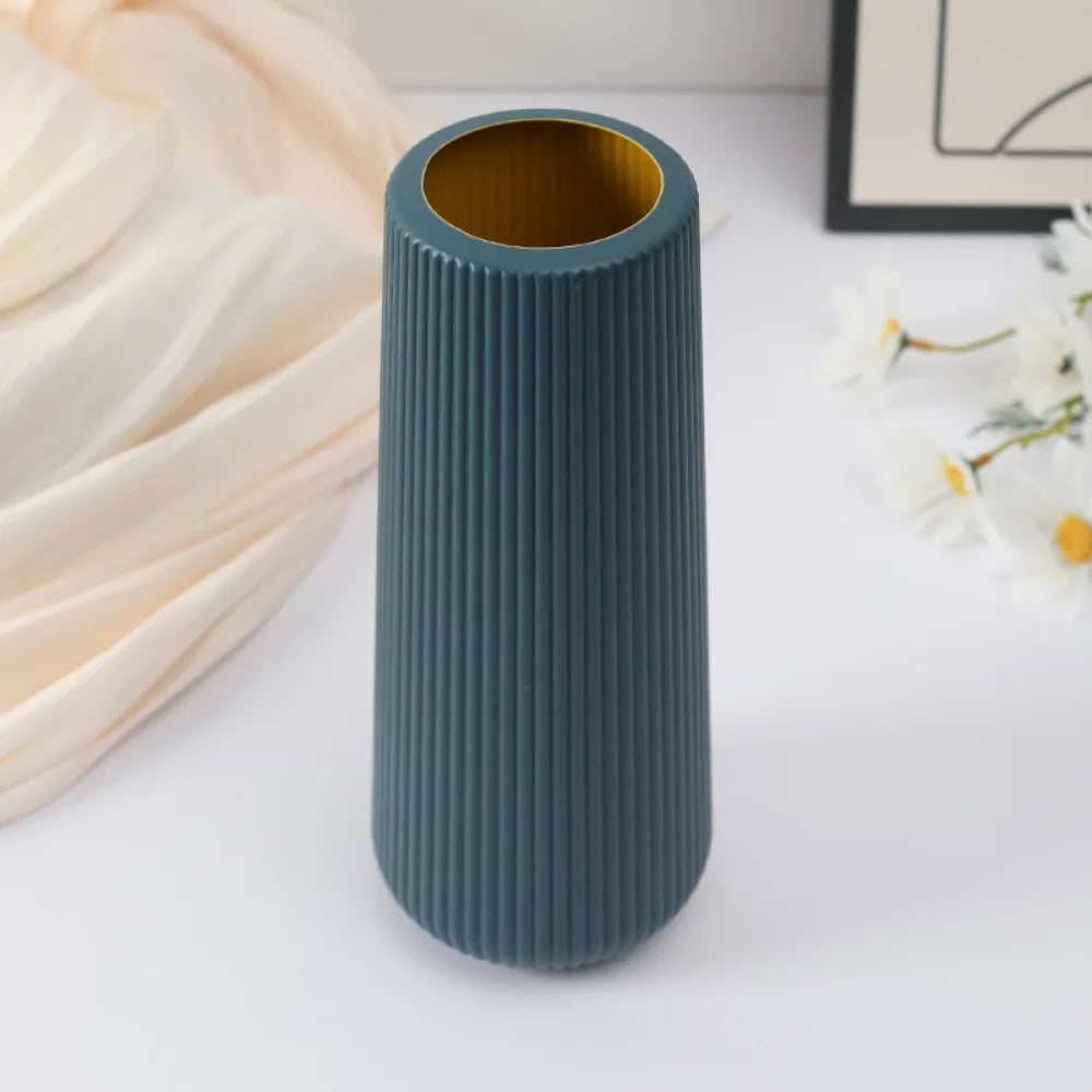 A tall, ribbed, matte teal plastic vase with a wide opening is shown on a white surface.