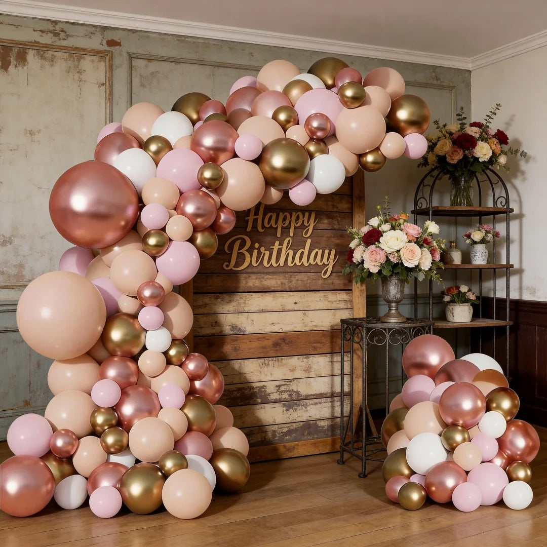 A large balloon garland featuring rose gold, pink, and beige balloons arranged against a wooden background.