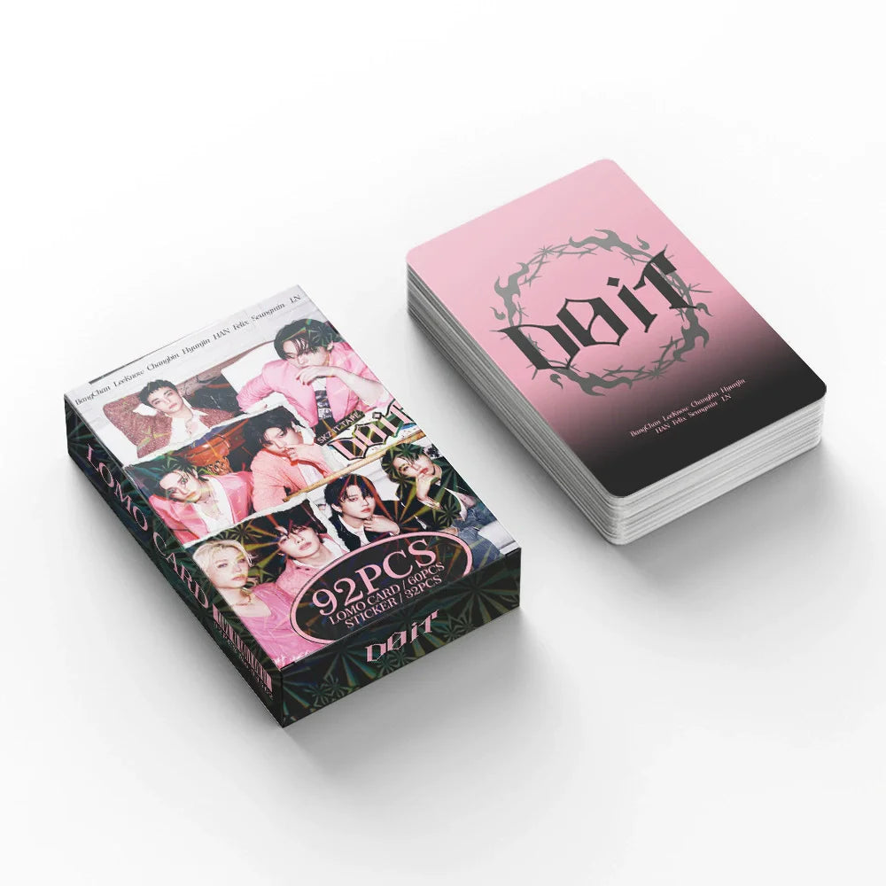 A stack of pink and black photo cards for Stray Kids featuring members and a logo.