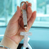 A hand holds a crystal letter keychain charm shaped like the letter T