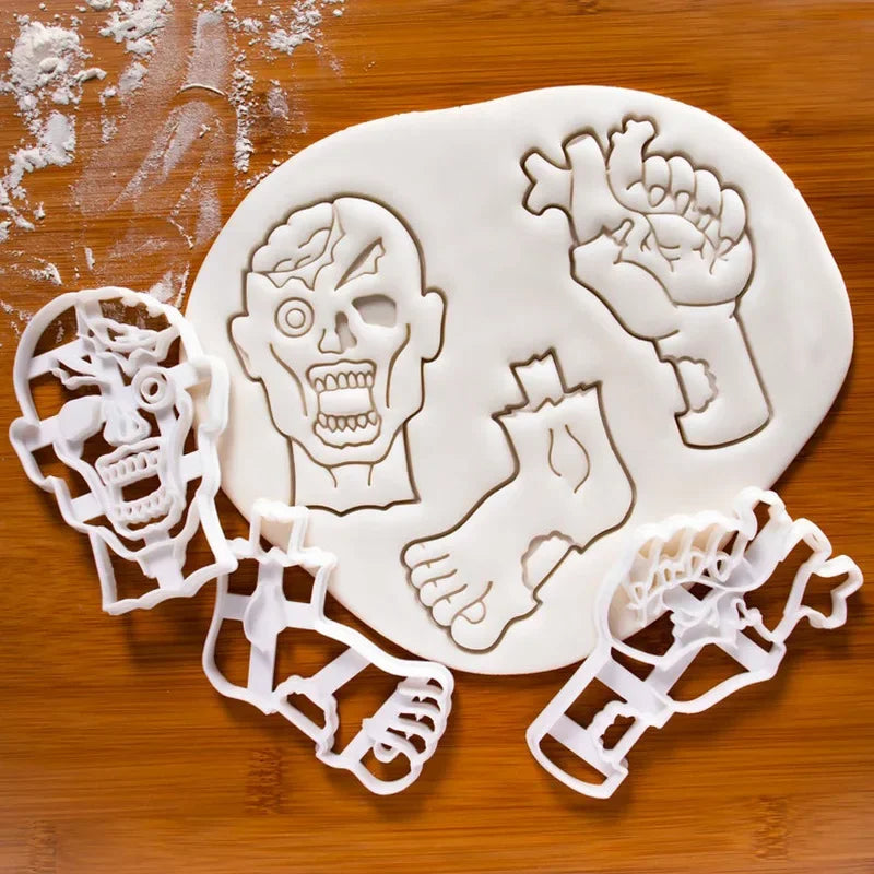 A set of white fondant and cookie cutters shaped like a skull, hand, foot, and various Halloween figures on a wooden surface.