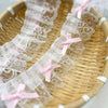 Delicate pink bow ruffle embroidery lace trim laid out on a woven bamboo tray