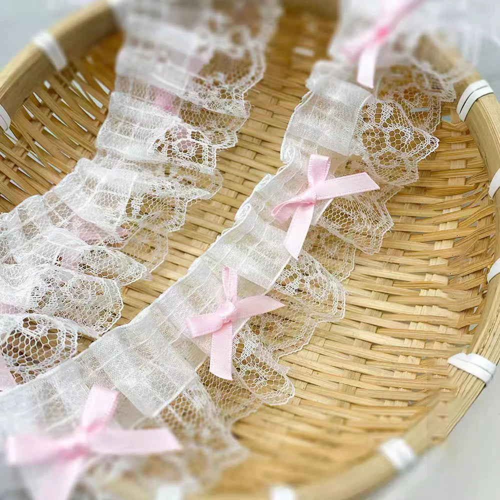 Delicate pink bow ruffle embroidery lace trim laid out on a woven bamboo tray