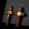 A wooden crucifix pendant with a figure of Christ and an inscription set against a dark gray background.