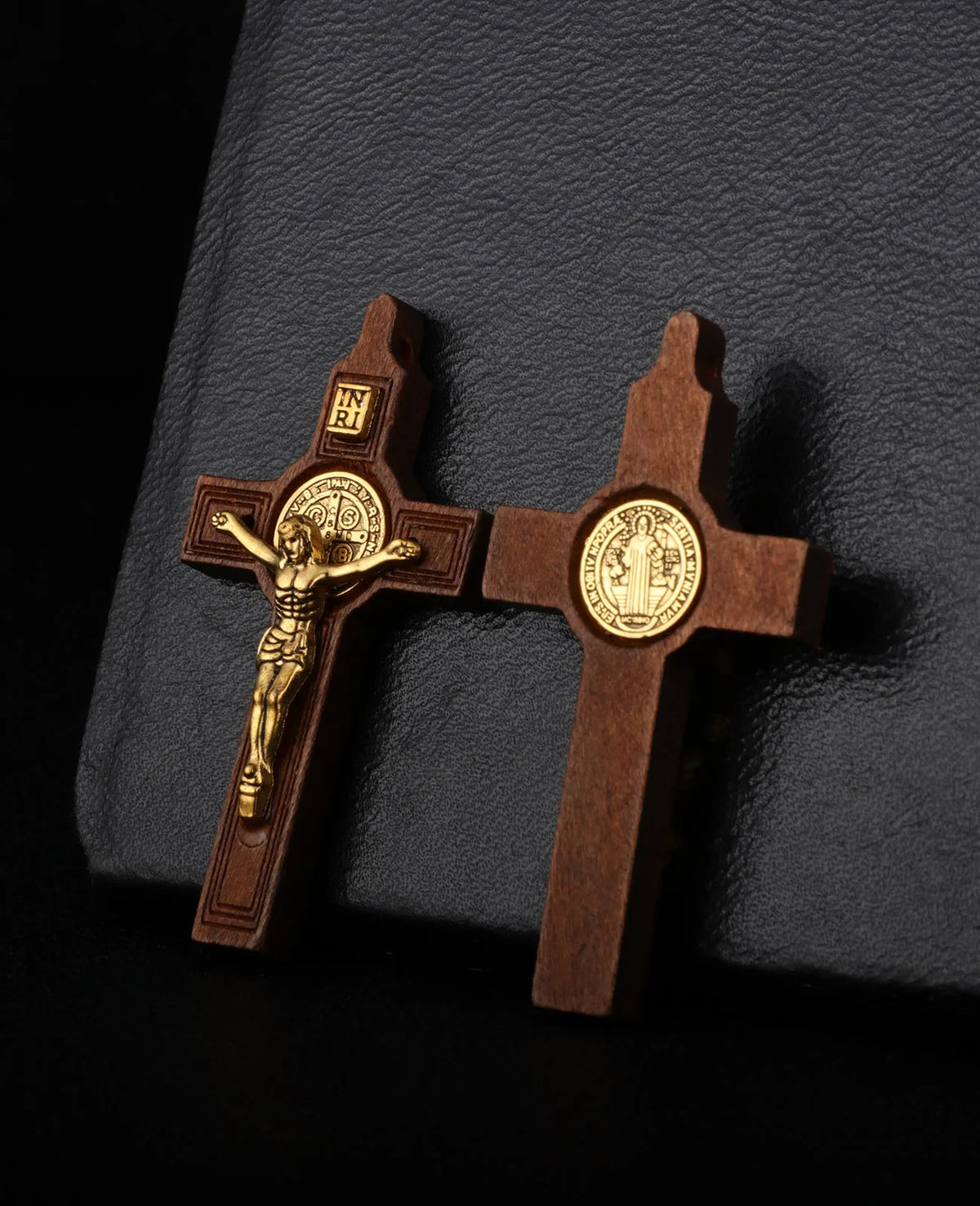 A wooden crucifix pendant with a figure of Christ and an inscription set against a dark gray background.