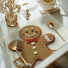 A set of four Christmas gingerbread man printed placemats on a light table setting.
