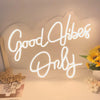 A large decorative LED neon sign spelling out Good Vibes Only on a white surface.