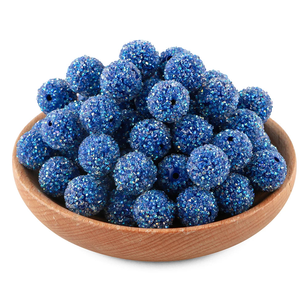 A pile of deep blue textured resin beads for jewelry making in a wooden bowl.