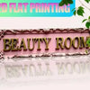 A vintage retro metal sign with the words BEAUTY ROOM in gold lettering on a pink background.