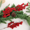 A branch of green pine needles decorated with clusters of bright red artificial holly berries for Christmas decor