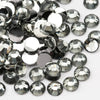 A close-up view of small, round flatback resin rhinestones in silver and clear tones scattered on a white background.