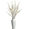 A branch of real touch faux plum blossoms with stems in a white vase.