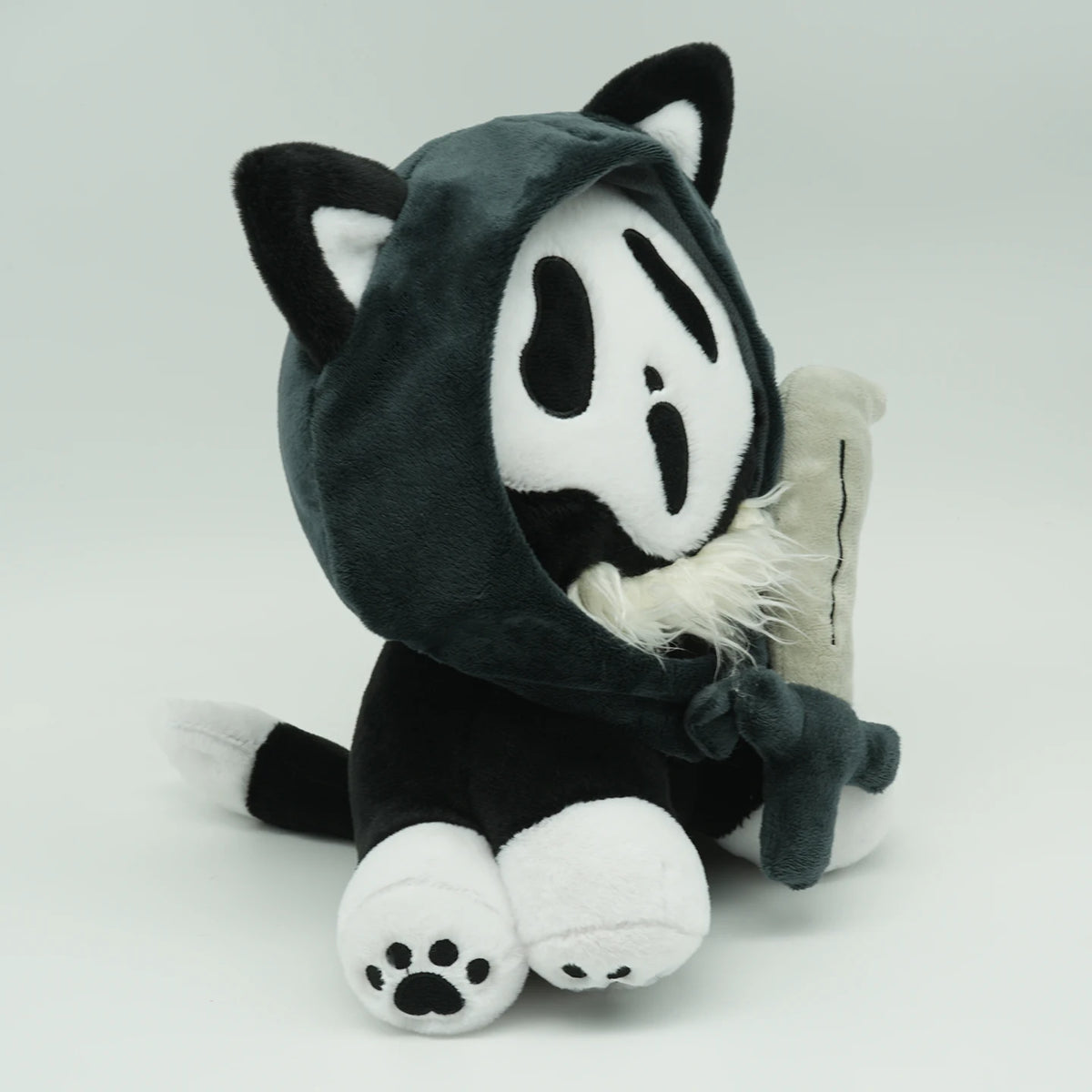 A dark gray and white plush toy resembling a cat with large ears and a hood.