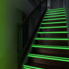Escalier en bois foncé avec des bandes LED vertes illuminant les marches et la balustrade.