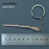 A miniature alloy gun model keychain with a light beige finish is shown next to a ruler for scale.