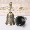 An ornate brass hand call bell with a decorative floral design and a curved handle.