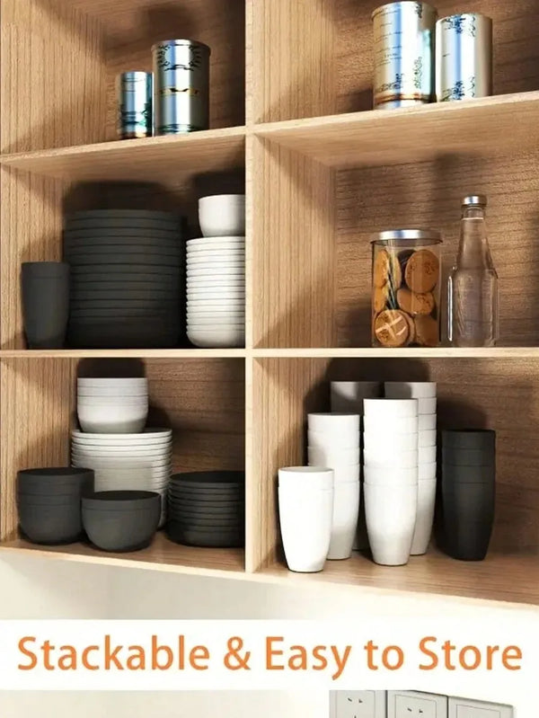 A set of stackable reusable plastic tableware in various shades of gray and white stored on wooden shelves.