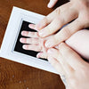 Hands print on a white frame showing baby handprint and footprint ink pad kit