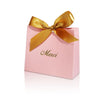 Pink paperboard gift box tied with a gold ribbon and the word Merci written on it.