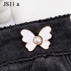 A white and gold pearl butterfly button attached to a black denim fabric.