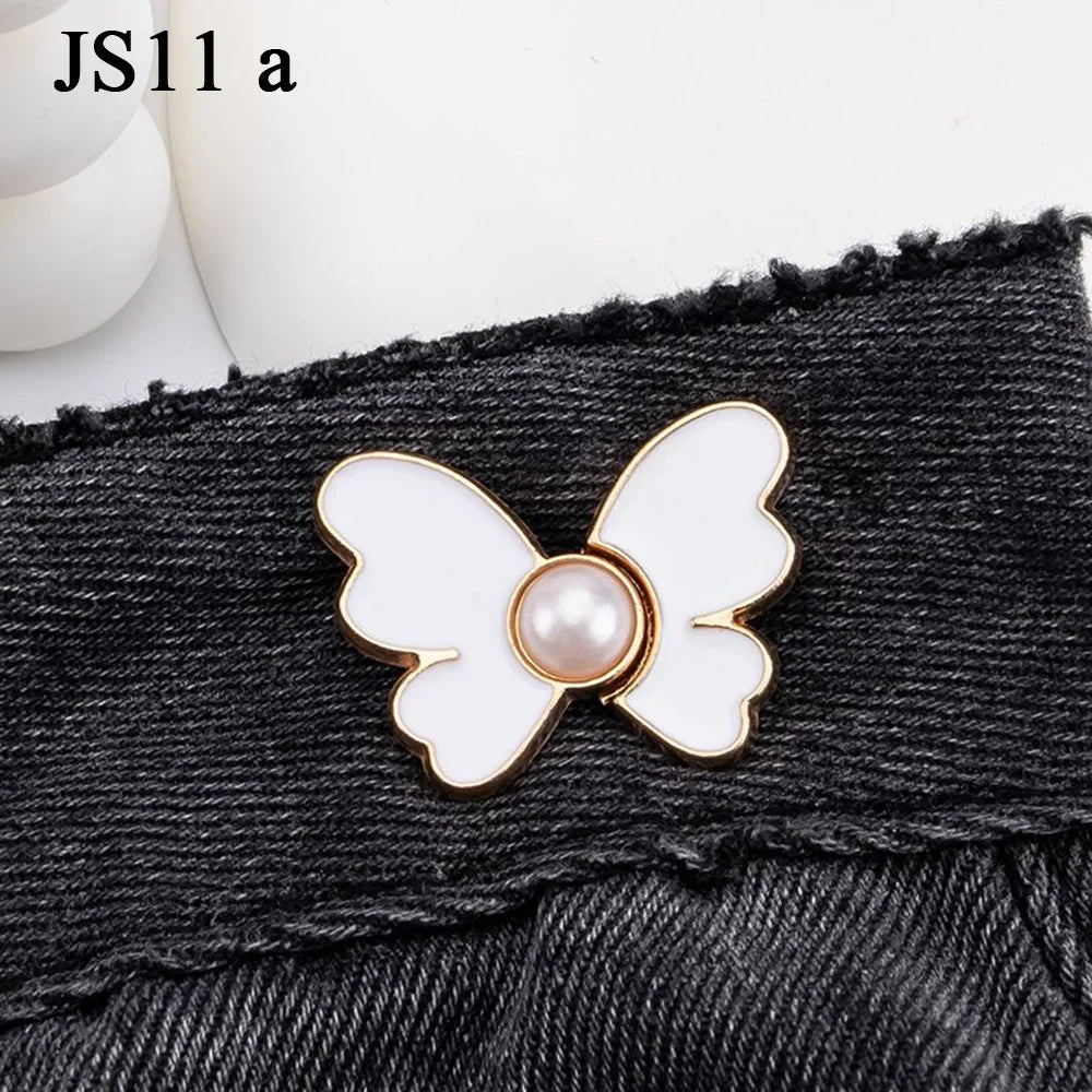 A white and gold pearl butterfly button attached to a black denim fabric.