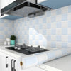 A kitchen countertop with a black stovetop and white cabinets, featuring blue tiled backsplash and a roll of waterproof oil-p